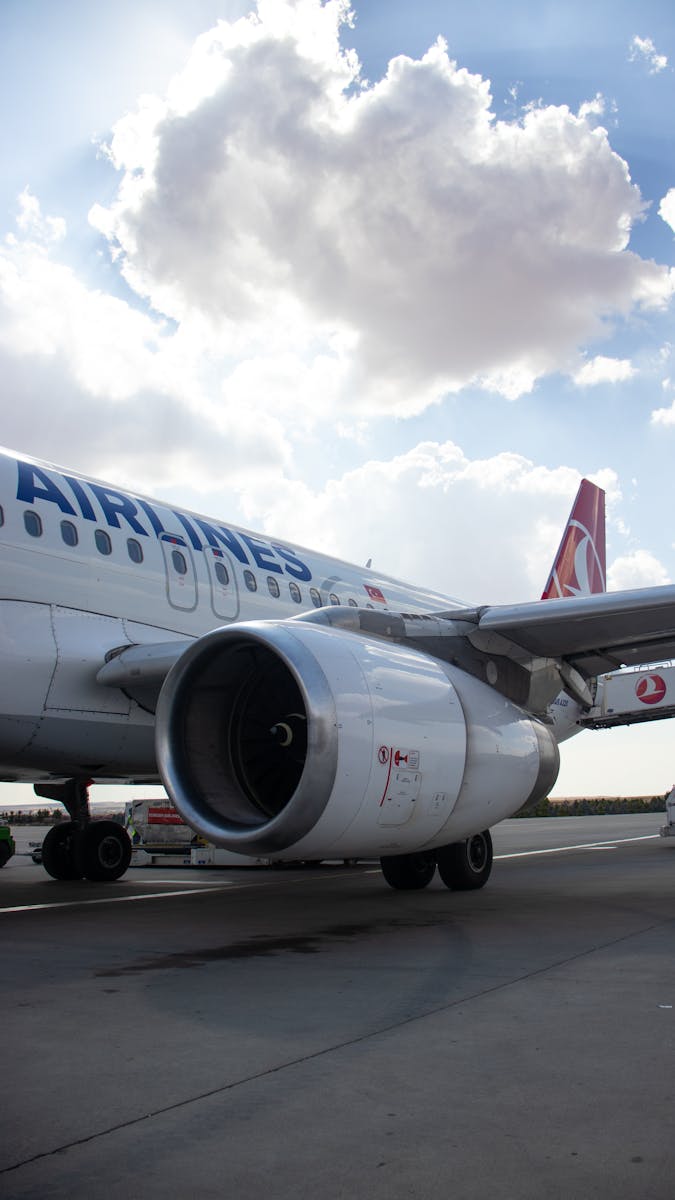 A detailed view of an airplane engine on the tarmac under a bright sky.